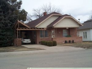 This Craftsman bungalow was updated in the late 1950's in an effort to make it more like a ranch house by emphasizing the horizontal. Gone are the bulky battered porch posts of the past. New brick veneer, picture windows and delicate structural ironwork gave the house more contemporary lines. The jaunty porte-cochère relates to the house in that it mimics the original open rafter tails of the eaves. Sadly, this quirky remodeling has just been remodled again... just as it was starting to get interesting.
