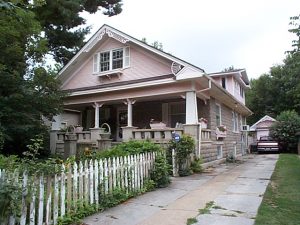 When built, this house Craftsman-style house possessed a rugged handsomeness characteristic of the Arts and Crafts era. The weighty front gable, masonry balustrade and rusticated block walls give this house a visual heft that no amount of pink paint, spindled fretwork and shutters can obscure.